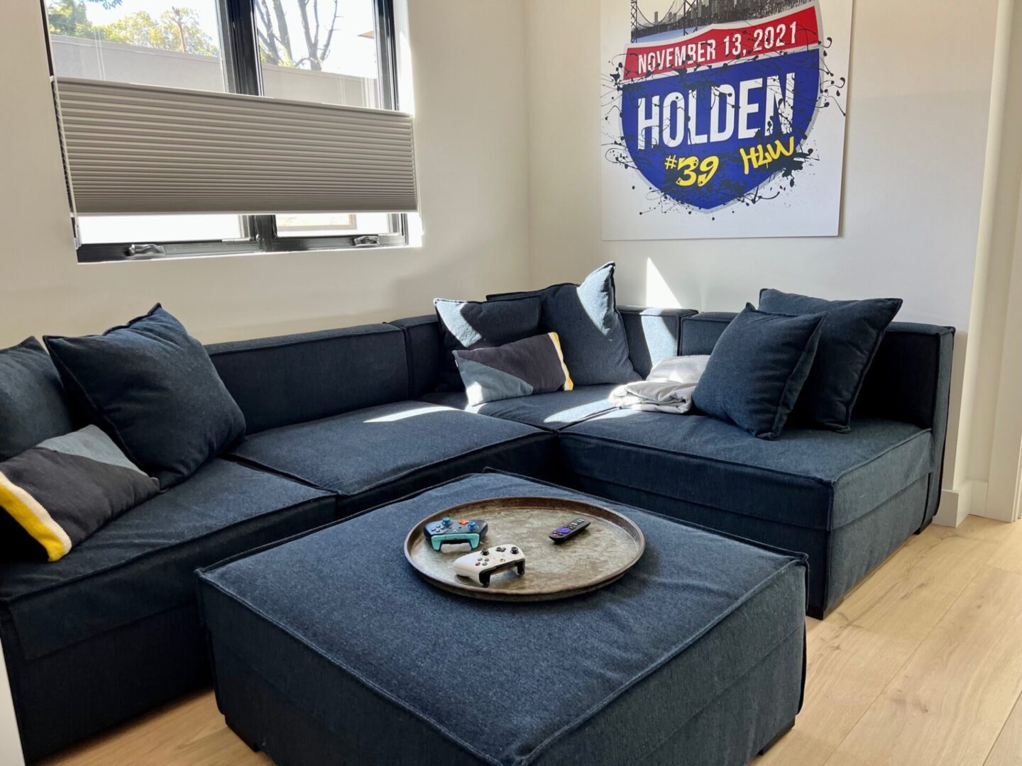 A blue sectional couch with ottoman and coffee table.