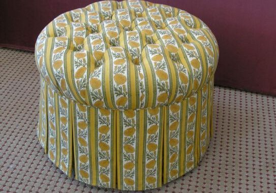 A round ottoman with yellow and white pattern.